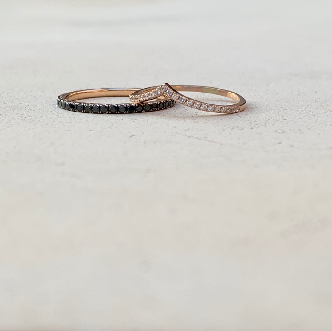 Two gold rings with black gemstones are placed on a white surface.