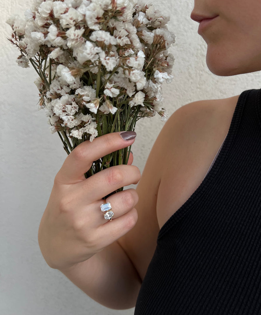 A woman holds a bouquet of white flowers in her hand, with a ring visible on her finger.