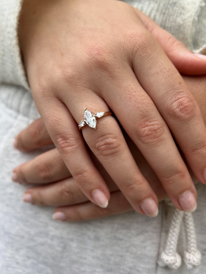 A close-up of a person's hand wearing a diamond engagement ring.