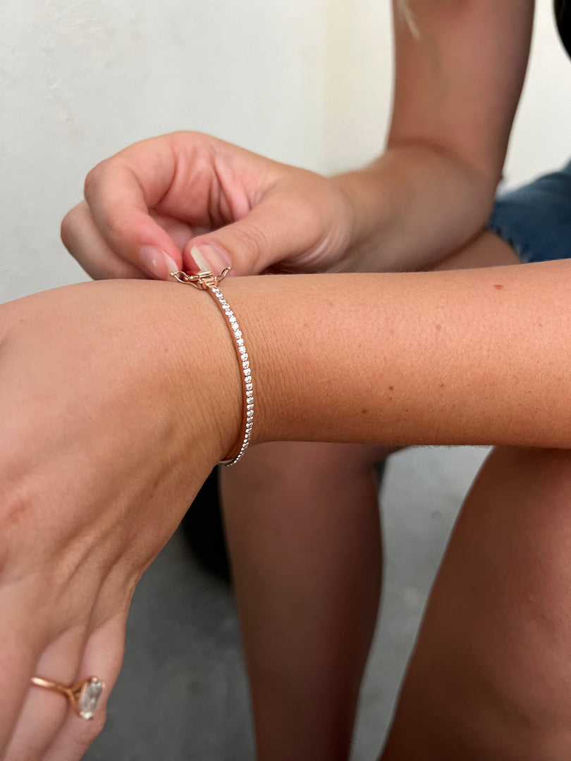 A close-up view of a person's wrist wearing a gold-colored bracelet with a diamond-like design.