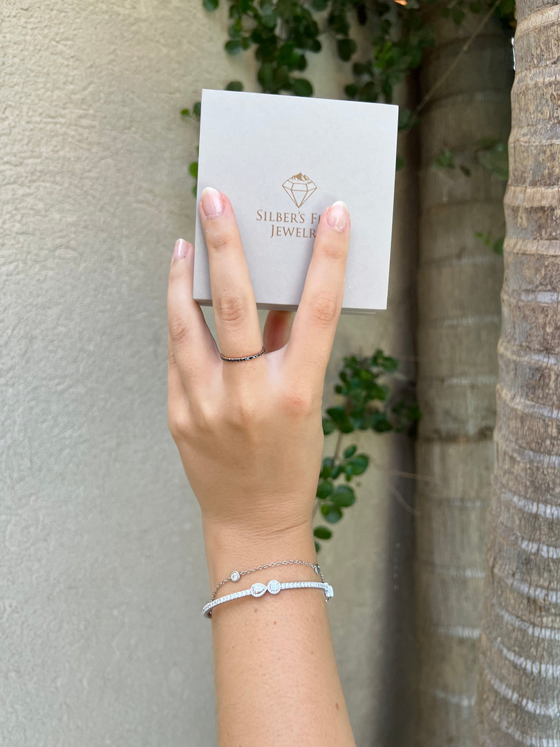 A hand holding a small box with the text "SILVER FASHION JEWELS" on it, along with a bracelet on the wrist.