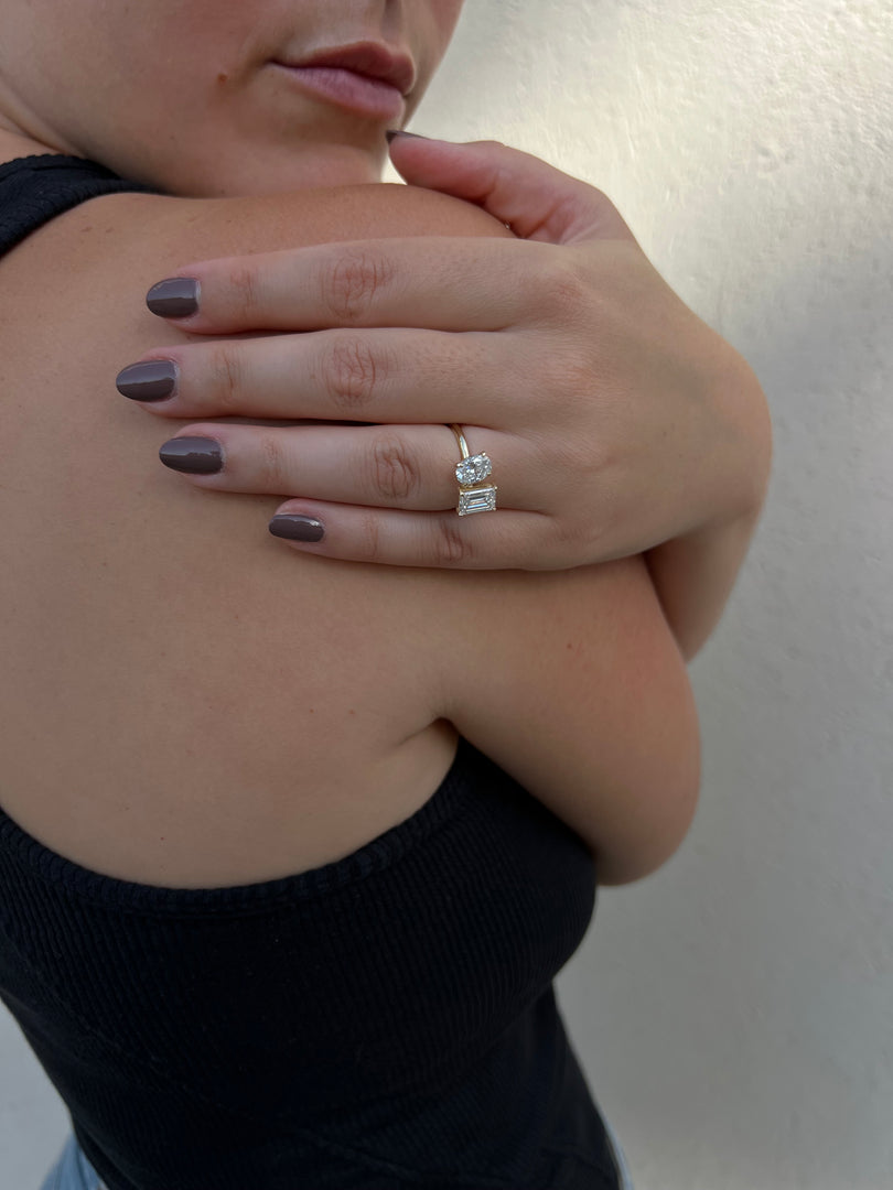 A close-up of a person's hand wearing a ring, resting on their shoulder.
