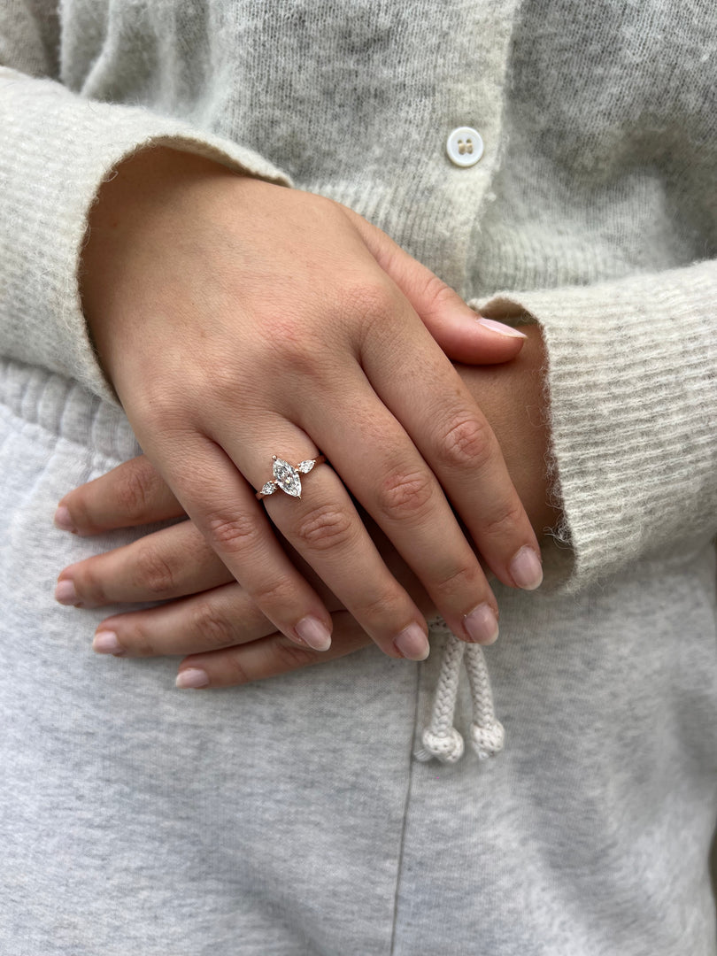 A close-up image of a person's hand wearing a diamond engagement ring.