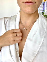 A close-up of a person wearing a white robe and a necklace with two pendants.