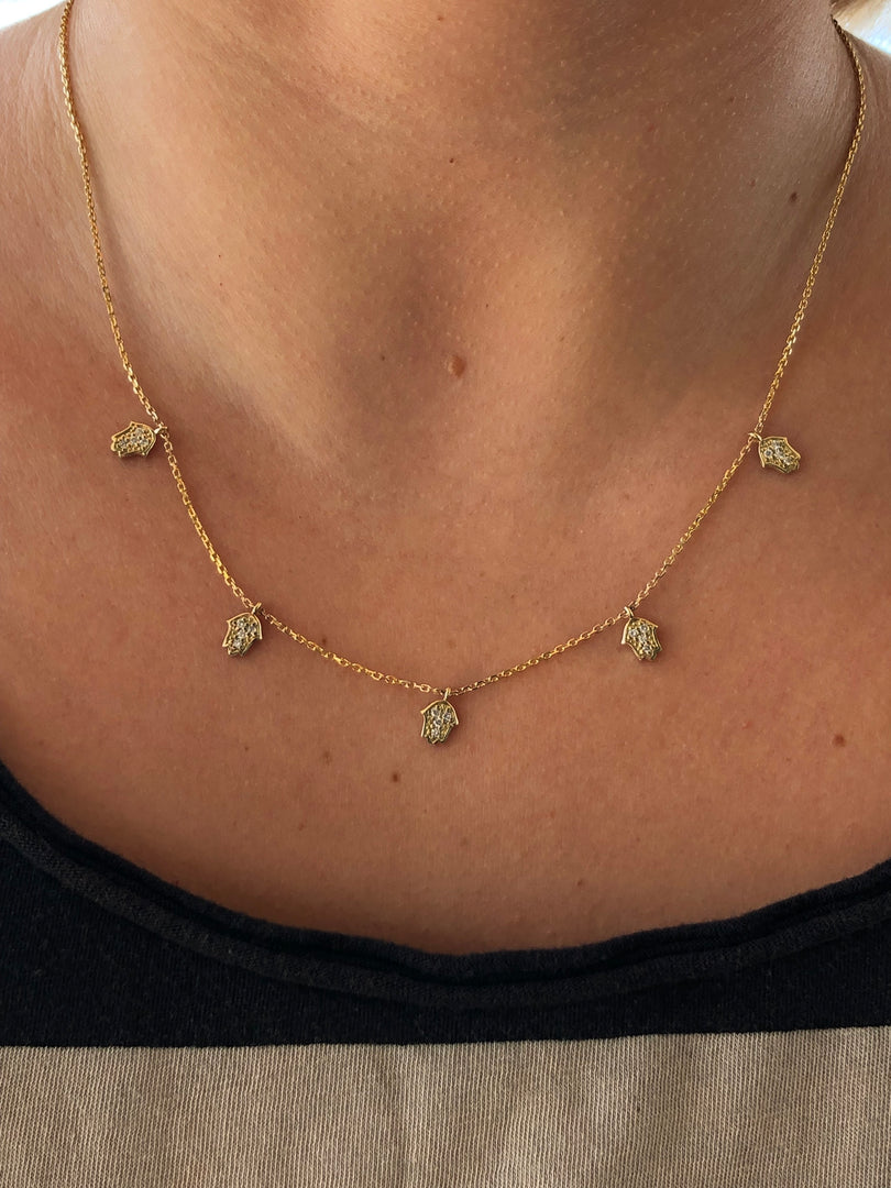 A close-up view of a gold necklace with small pendants on a person's neck.