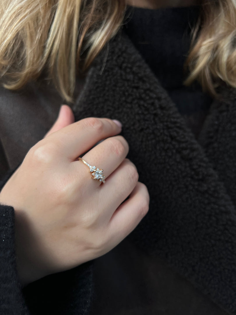 A close-up view of a person's hand wearing a gold ring with a diamond center stone.