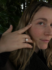 A close-up of a person's hand with a ring on it, resting on their finger, with their hair visible.