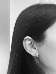 A close-up of a person's ear with a diamond earring, captured in black and white.