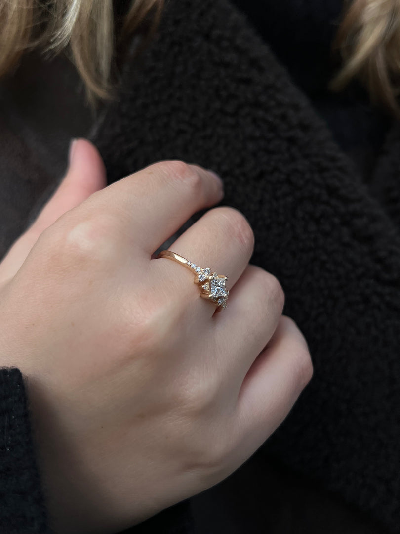 A close-up of a person's hand wearing a gold ring with a diamond center stone.