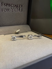 a pair of diamond earrings placed on a gray fabric surface, with the text 