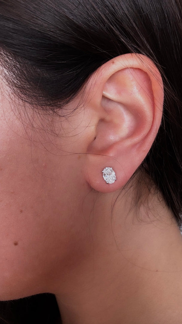 A close-up of a person's ear with a diamond earring in the earlobe.