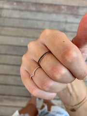 A close-up view of a person's hand wearing two rings, one with a black band and the other with a white band.