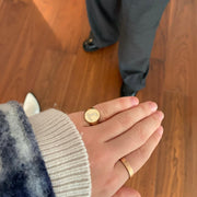 A close-up of a person's hand wearing two gold rings, one with a diamond design and the other with a simple band.