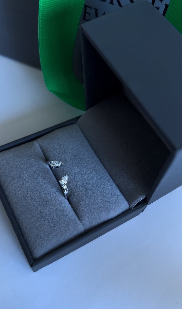 A pair of silver earrings is displayed in a black jewelry box on a white surface.